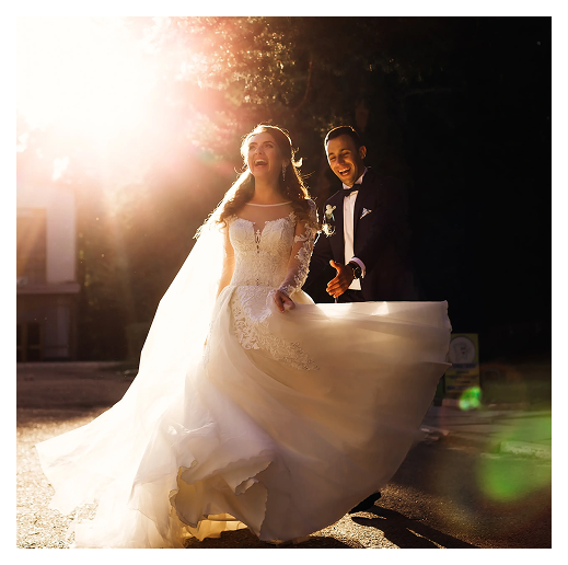 Bride and groom joyfully walking in sunlight.